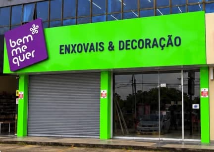 Fachada da loja Enxovais Bem Me Quer, com letreiro verde e a logo roxa